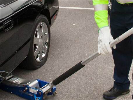 Roadside assistance service person lifting a car with a hydraulic jack