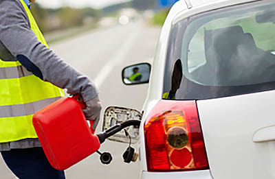 Roadside assistance service person delivering fuel with small red plastic gas can