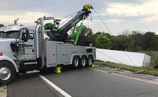 Heavy duty tow truck pulling semi trailer from ditch with tow cables